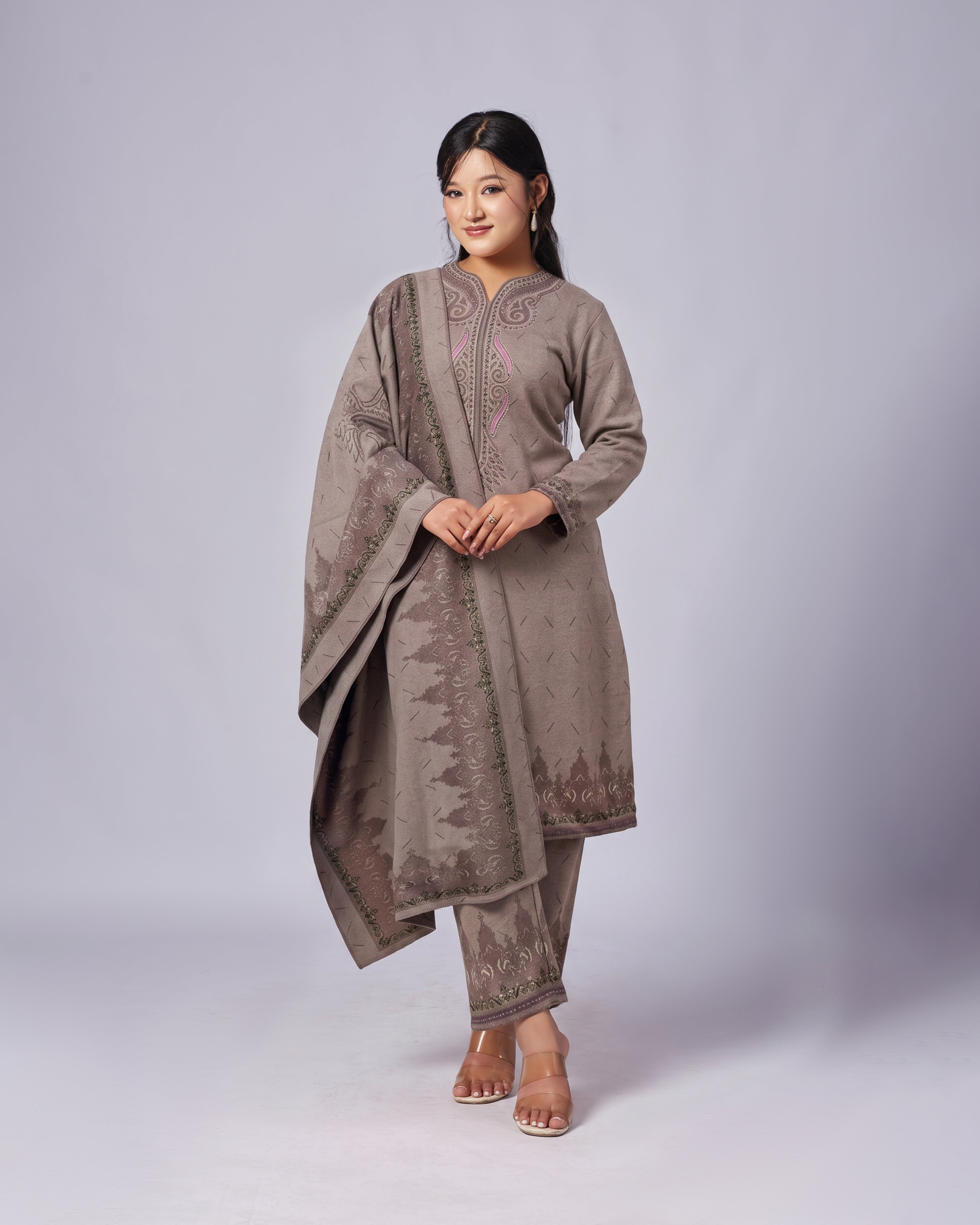 Woman wearing a traditional outfit with a draped fabric on a plain background