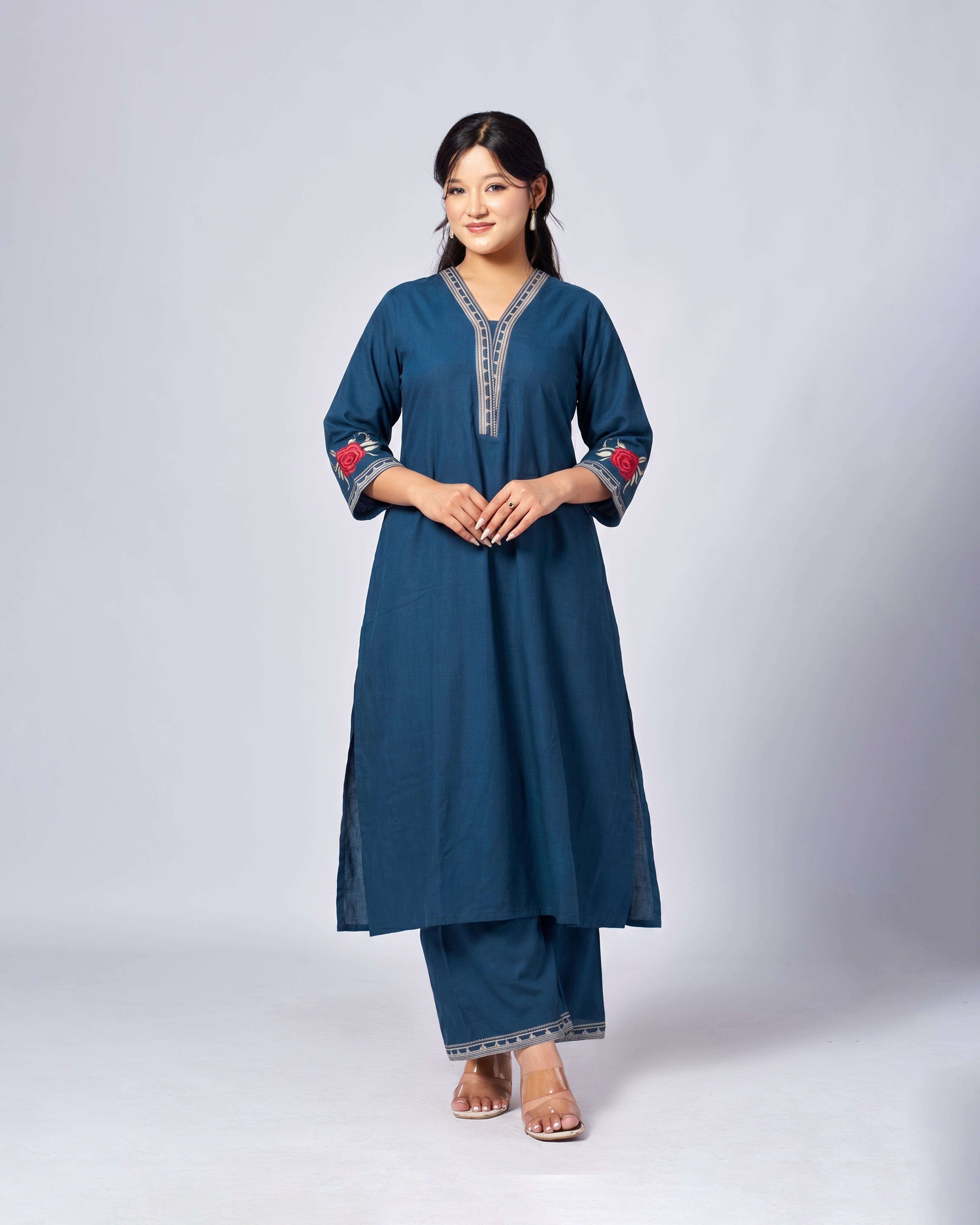 Woman wearing a blue traditional outfit with red embroidery on a white background