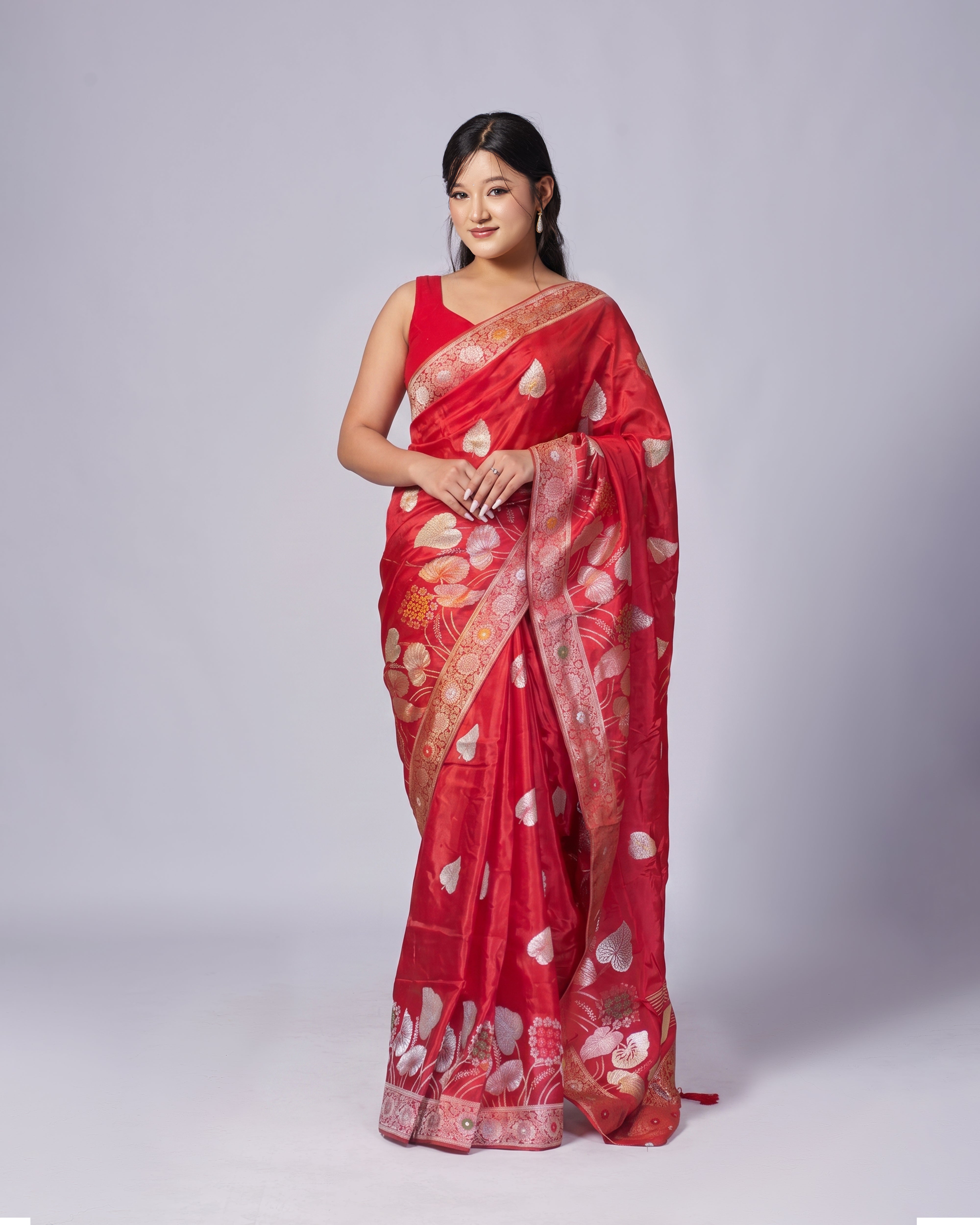 Woman wearing a red saree with white patterns on a white background