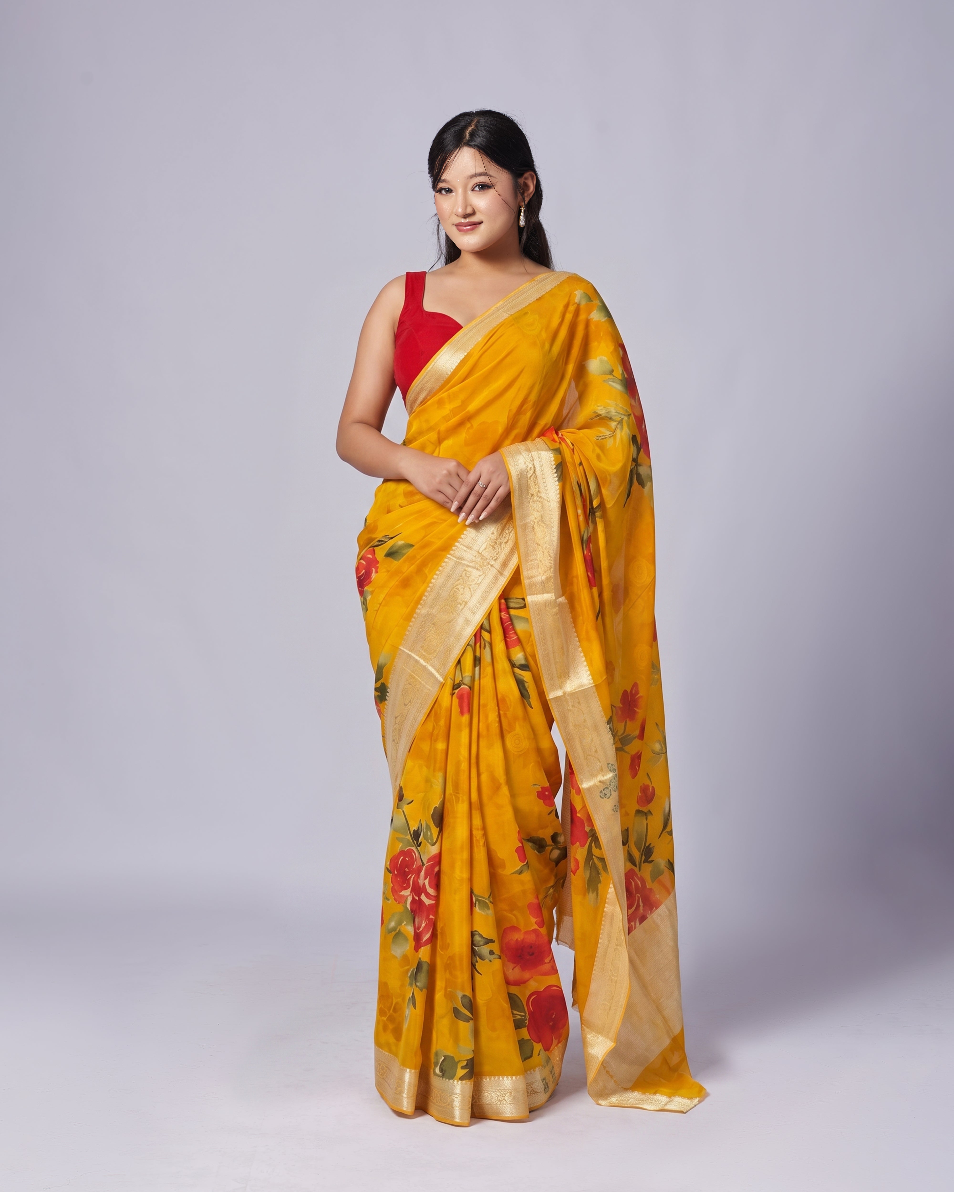 Woman wearing a yellow saree with floral patterns on a plain background