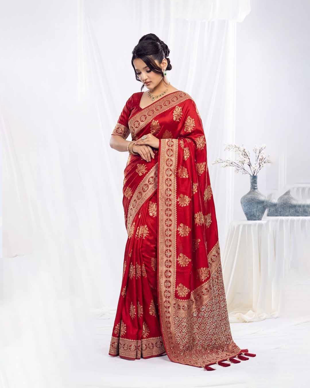Woman wearing a red saree with gold patterns on a white background